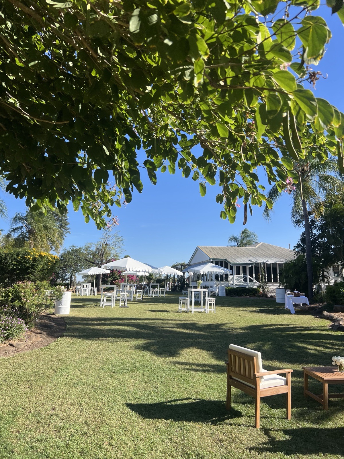 Cocktail lounge and white market umbrellas set on pristine homestead lawns at Kemmis Station Mackay